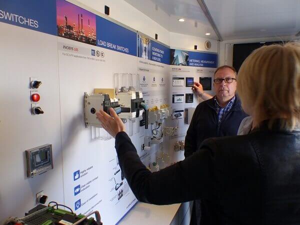 Eine Person präsentiert einer anderen Person elektrotechnische Komponenten.
