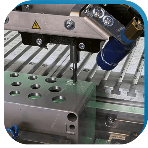 Bildhintergruende_Datron_02 Die CNC-Fräsmaschine DATRON M8Cube in Nahaufnahme beim Fräsen von Löchern in ein Gehäuse.